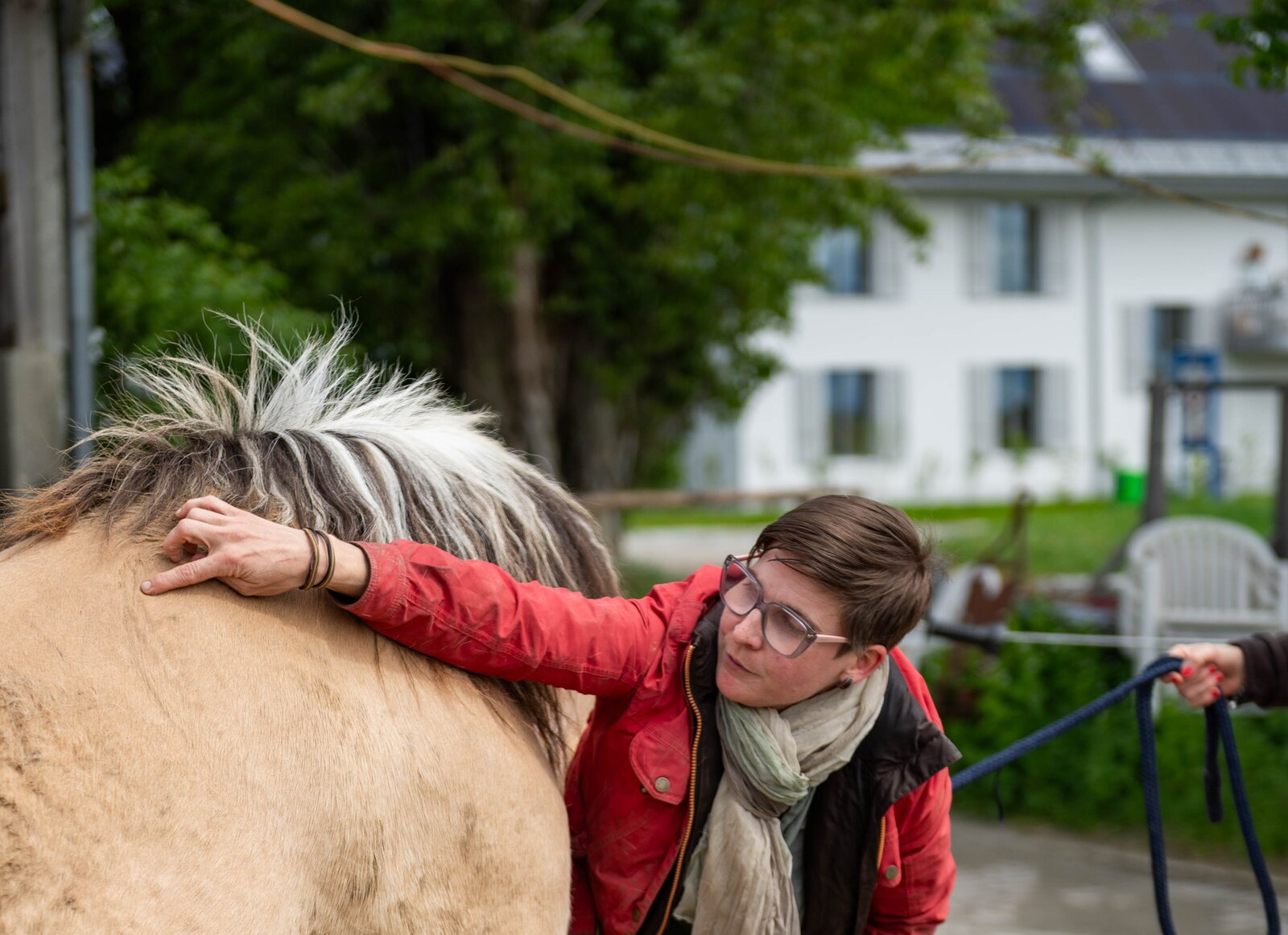 Esther Wymann posant la main sur l'encolure d'un cheval, en extérieur
